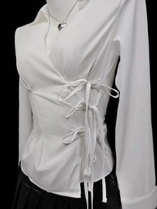 Detail of white wrap shirt with side bow ties and V-neckline on a female mannequin