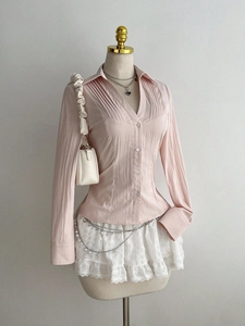 Close-up of pale pink pleated texture women shirt featuring V-neck and delicate buttons