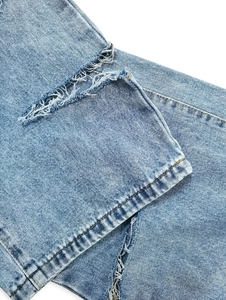 Dettaglio di jeans azzurri strappati che mostrano bordi consumati e trama denim