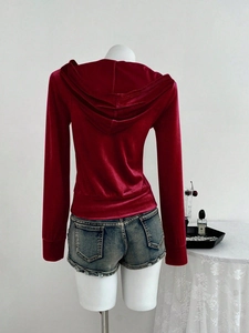 Detail van rode fluwelen hoodie met vintage denim shorts op een mannequin gepresenteerd