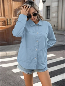 Close-up of light blue denim shirt jacket with large pockets and button closure in street style