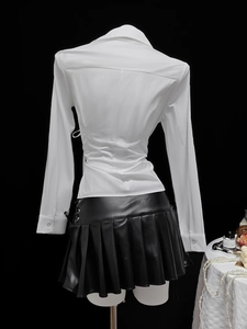 Detail of waist pleated white shirt paired with black faux leather pleated mini skirt