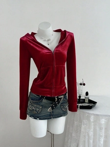 Detail van rode fluwelen hoodie met rits gecombineerd met denim minirok en riem