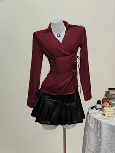 Women's wine red wrap blouse with side bow ties and black pleated faux leather skirt
