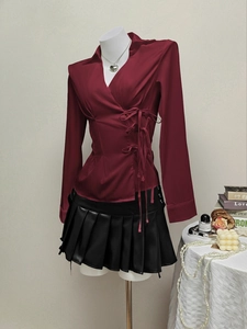 Deep red wrap blouse with V-neck and side bow details paired with black pleated skirt