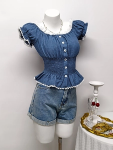 Dettaglio del top blu scuro con bordo in pizzo e vita a punto smock con volant