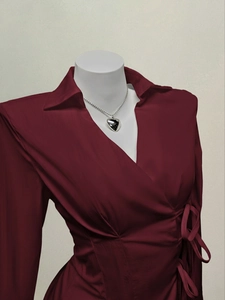 Detail of burgundy wrap shirt featuring V-neck collar and side tie decoration