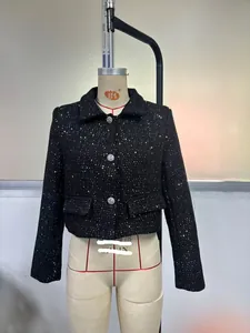Close-up of black sequined tweed jacket featuring decorative gem buttons and flap pockets