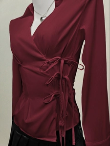 Detailed view of dark red blouse with side drawstring bows and elegant V-neckline design