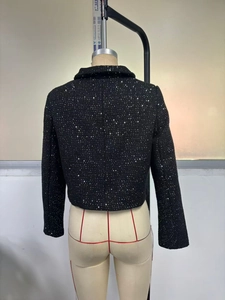 Macro shot of back stitching on black sequin tweed jacket on mannequin