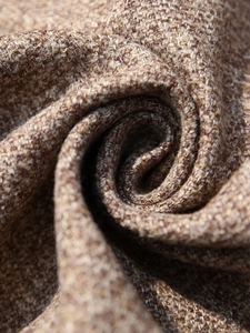 Close-up of brown wool blend tweed fabric showing its rich woven texture and drape