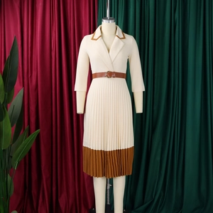 Detail des eleganten beigen Plisseekleids mit kontrastierendem braunem Revers und Saum
