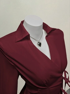 Detail of burgundy wrap blouse featuring long sleeves, lapel collar, and waist tie design