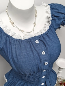 Dettaglio dello scollo a U con bordo in pizzo a fiori bianchi e bottoni floreali decorativi