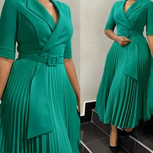Close-up of emerald green pleated dress with lapel collar and matching belt details