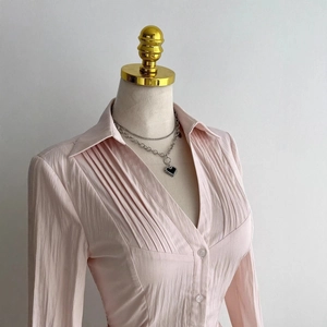 Light pink long sleeve pleated V-neck blouse for women on mannequin with necklace