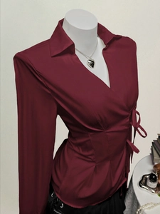Detail of burgundy V-neck wrap shirt with side tie waist and long sleeves on a mannequin