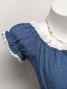Dettaglio del top blu effetto denim con ricamo in pizzo floreale sulle maniche a sbuffo