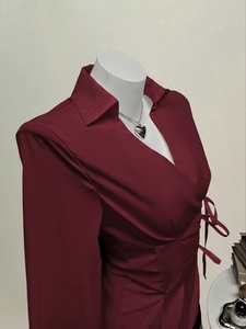 Detail of burgundy long sleeve shirt featuring side drawstring waist and silky texture