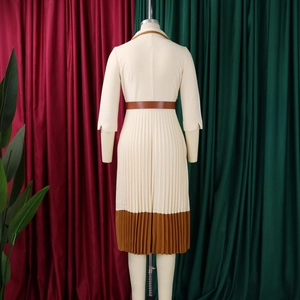 Detail eines eleganten cremefarbenen Faltenkleids mit braunem Kragen und Gürtel