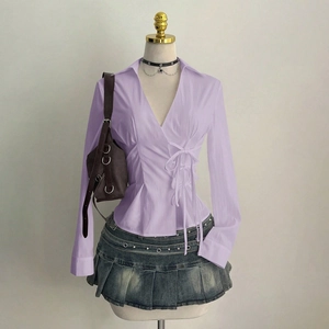 Detail of lavender v-neck wrap shirt with side ties paired with pleated denim skirt
