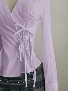 Detail of light purple V-neck blouse featuring side bow tie knots and waist cinching design