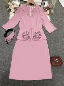 Détail d'une robe crayon rose montrant des fleurs en tissu 3D et une ceinture assortie