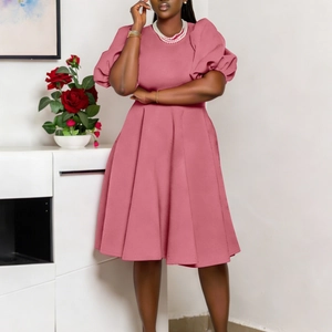 Detail of elegant lotus pink dress featuring chic puff sleeves and a pleated skirt hem