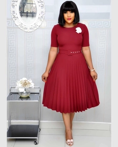 Detail of burgundy pleated dress with waist belt and white floral brooch on the chest