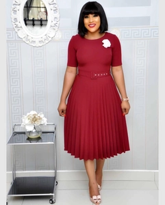 Detail of burgundy pleated midi dress with round neck, matching belt and floral brooch
