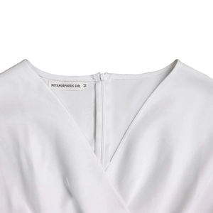 Detail view of a white V-neck dress featuring an invisible zipper and brand label on neckline