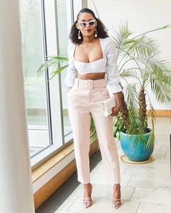 Women's chic light pink high-waisted suit pants with a matching belt and white crop top