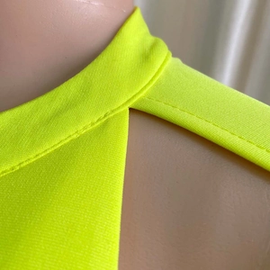 Dettaglio del tessuto a maglia giallo neon con cuciture a vita alta e finiture curate