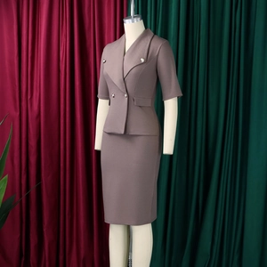 Détail d'un tailleur-jupe taupe à manches courtes et double boutonnage avec boutons dorés