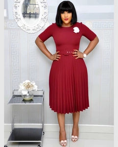 Detail view of the wine red pleated dress featuring a white floral brooch and waist belt