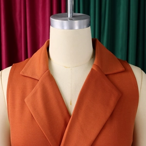 Close-up of orange sleeveless blazer jumpsuit collar and textured fabric detail