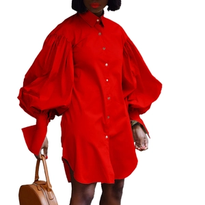 Détail de robe chemise rouge à manches longues avec manches bouffantes et boutons