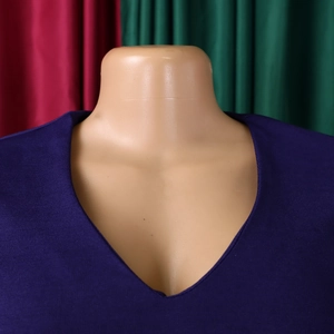 Detailed view of deep V-neckline on purple textured dress with pleated half sleeves