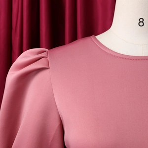 Detail of round neckline and puff sleeve pleats on a dusty pink textured dress