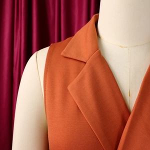 Detail of orange sleeveless jumpsuit with notch lapels and premium twill texture