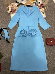 Détail de robe midi bleu clair avec accents de roses en tissu 3D et ceinture assortie