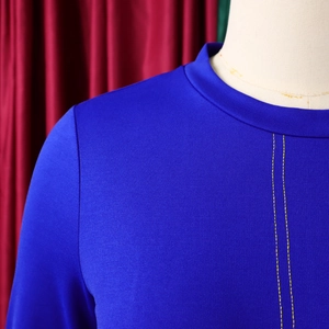 Dettaglio di un abito in maglia blu reale con cuciture gialle verticali e scollo rotondo