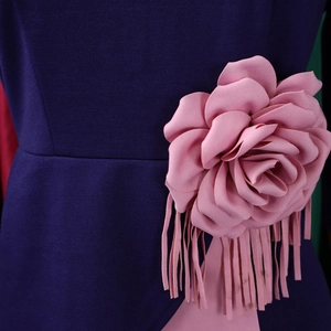 Detailed macro view of 3D pink fabric flower with fringe on deep purple dress waist