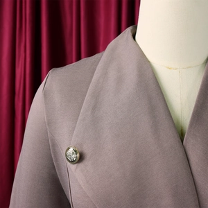 Détail de la robe blazer avec revers en pointe et bouton argenté à motif de blason gravé