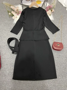 Détail à plat d'une robe crayon noire à basque avec manches mi-longues et ceinture