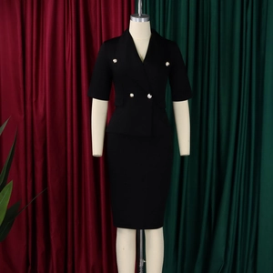 Détail d'un tailleur deux pièces noir avec boutons dorés et jupe crayon sur un mannequin