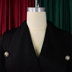 Détail d'un blazer noir avec boutons dorés en relief au design de style Médusa