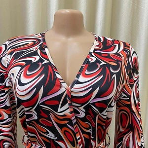Detail of the V-neck wrap design and bold African fire print on this long sleeve jumpsuit