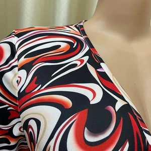 Close-up of the V-neckline and bold abstract swirl print fabric on women's jumpsuit