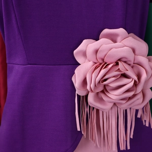 Detail of pink fabric rose and long fringe on dark purple pleated African dress waist